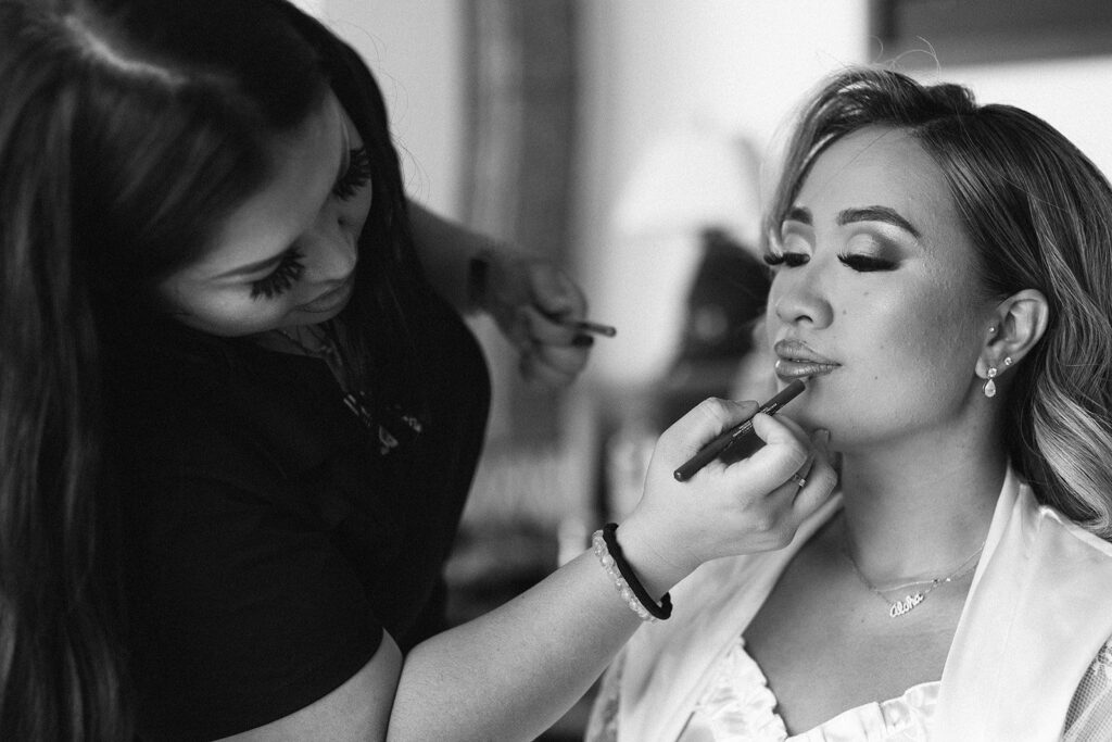 bride getting lipstick on by make up artist 