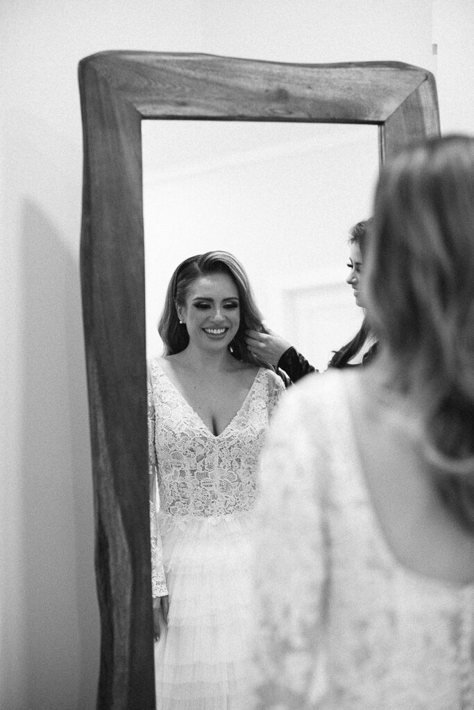 Bride standing in front of the mirror while her mom adjust her hair 
