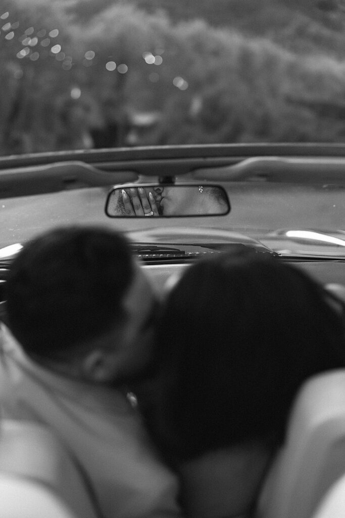 Bride and groom kissing out of focus and in focus in rear view mirror 