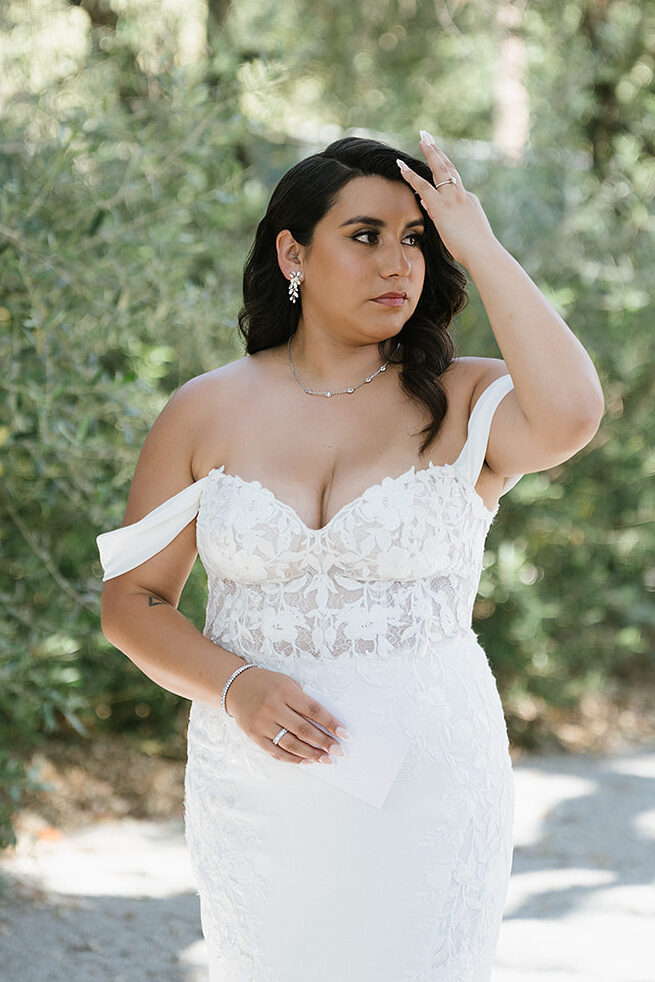 Bride fixing her hair in a white dress while holding her vows