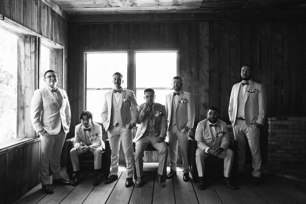 Black and white photo of a groom and his groomsmen some sitting some standing looking serious 